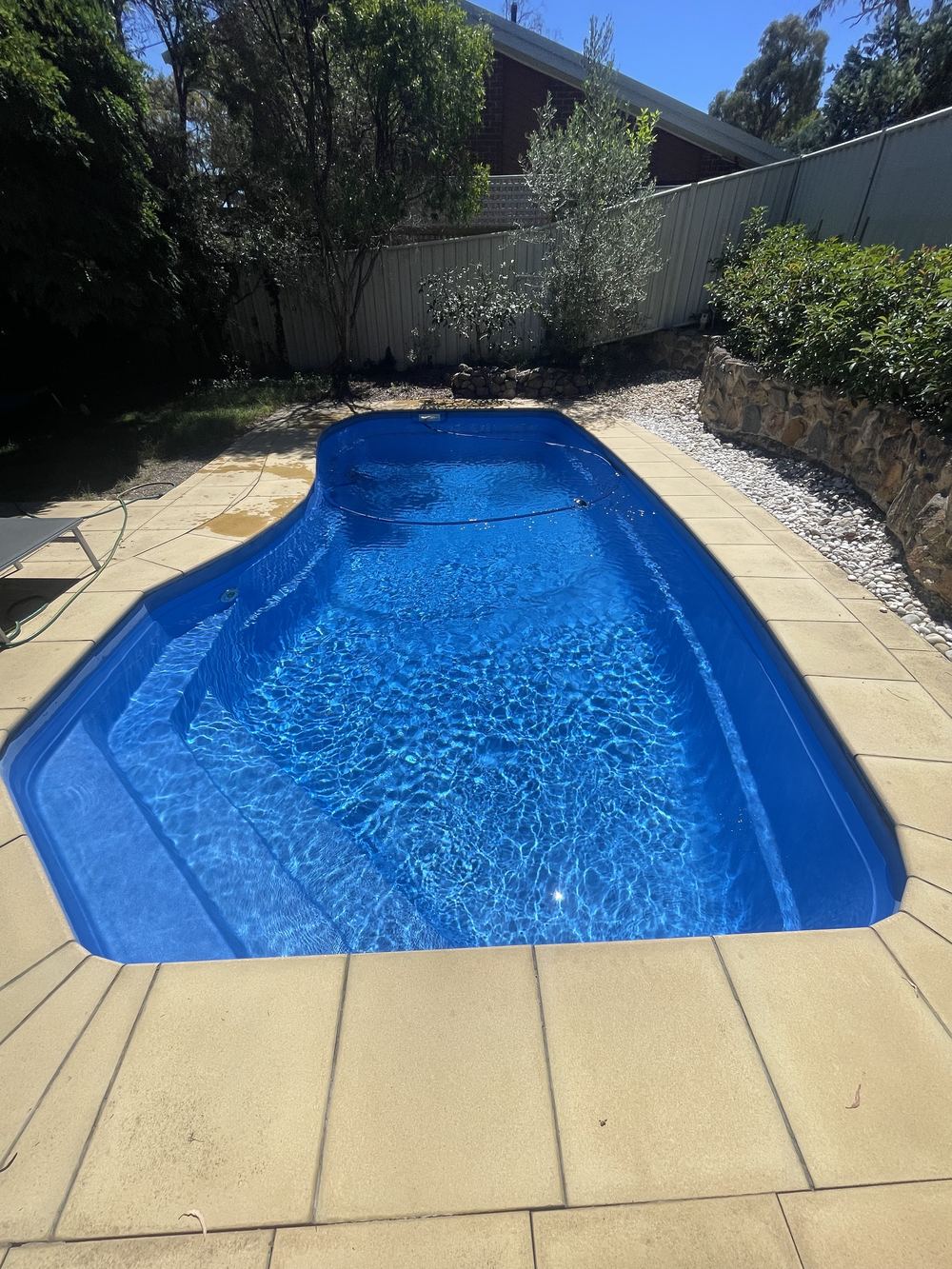 Pool vacuum hose beside a freshly cleaned backyard pool in Canberra